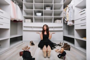 custom closet vs pre-built closet beautiful young woman sitting floor big nice dressing room around shoes doesnt know what wear is appointed tired making choice-wearing-black-dress-scaled.jpg