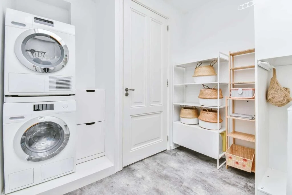 White laundry room with stacked machines and open shelving