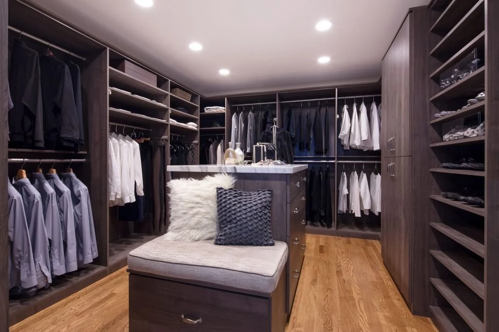 Dark walk-in wardrobe with a central storage island and bench